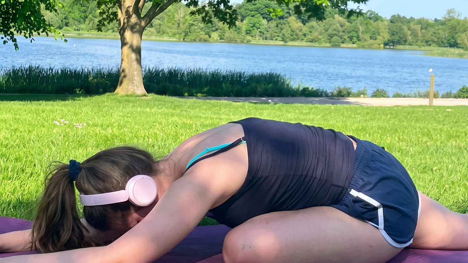 Nicole resting in child’s pose on a yoga mat by a lake
